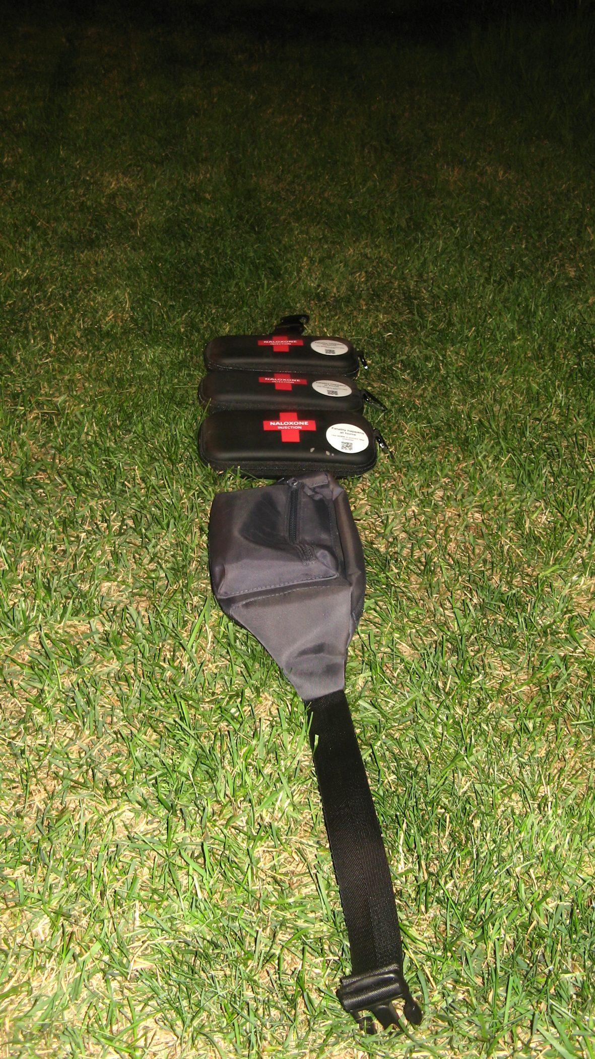 Tactical Compassion, crossbody bag with three naloxone kits laid flat on grass